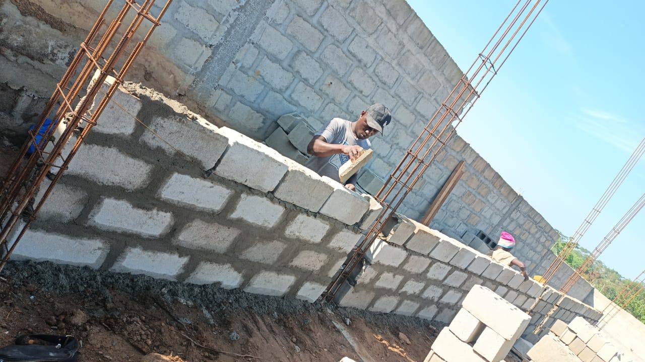 Artisan realisant un mur en blocs sur chantier